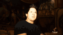 a man in a black shirt says nothing in front of a travel channel logo