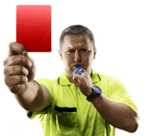 a man in a yellow shirt is blowing a whistle while holding up a red card