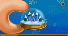 a hand holding a snow globe with a castle inside of it