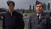 two men in military uniforms stand next to each other