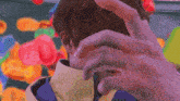 a person covering their face with their hand in front of a bunch of balloons .