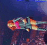 a woman in a pink top and blue skirt is holding a microphone on a stage