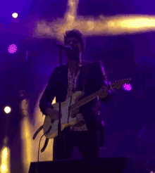 a man playing a guitar and singing into a microphone on a stage