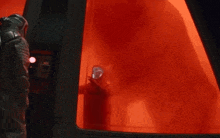 a man in a gas mask is standing in a room with red smoke coming out of a window .