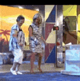 two women are dancing on a stage in front of a sign that says ' paradise ' on it .