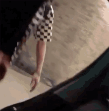 a person wearing a black and white checkered shirt is walking down a sidewalk .