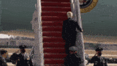 a man in a suit is walking up a set of stairs with a united states seal behind him