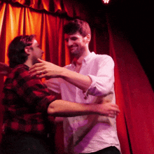 a man in a plaid shirt is hugging another man in a white shirt