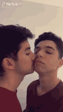 a couple of young men are kissing each other on the nose .