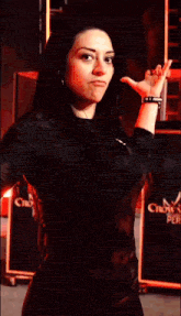 a woman in a black shirt is making a funny face while standing in front of a red background .