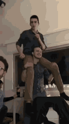 a man carrying another man on his shoulders in a room