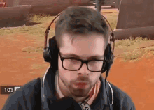 a man wearing headphones and glasses is looking at the camera .