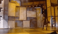 a person is walking on a stage in front of a wall with a pattern on it .