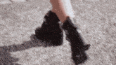 a close up of a person 's feet wearing black boots on a carpet .