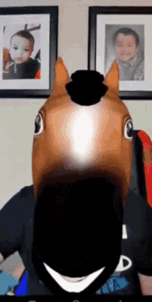 a person wearing a horse head mask in front of two framed pictures of a child
