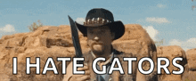 a man in a cowboy hat is holding a knife and says i hate gators .