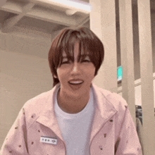a young man wearing a pink jacket and a white shirt is laughing .