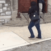 a woman is walking down a sidewalk while holding a purse and talking on a cell phone .