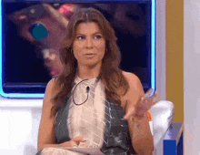 a woman is sitting in front of a television talking into a microphone while wearing headphones .