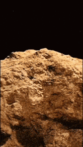 a large rock against a black background with a shadow on it