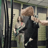 a man playing a guitar and a woman holding a microphone in a room