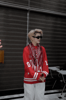 a man wearing sunglasses and a red sweater with the letter d on it
