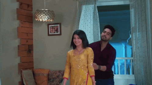 a man is putting a yellow dress on a woman .