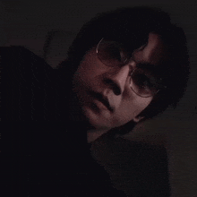 a man wearing glasses and a black shirt is looking at the camera