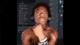 a shirtless man wearing headphones looks at the camera with his hand on his chin