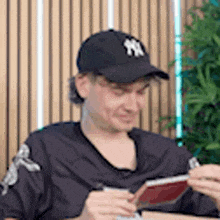 a man wearing a new york yankees hat is playing a video game on a nintendo 3ds .