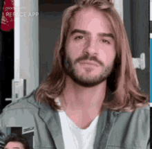 a man with long blonde hair and a beard is looking at the camera .