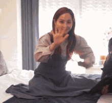 a woman is sitting on a bed with a blanket on her lap