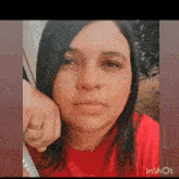 a woman wearing a red shirt and a wedding ring on her finger .