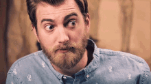 a man with a beard is wearing a denim shirt with a cactus print .