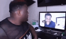 a man is sitting in front of a television watching a video .