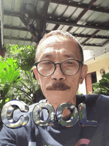 a man with glasses and a mustache has the word cool on his shirt