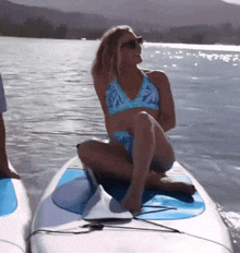 a woman in a bikini is sitting on a surfboard in the water