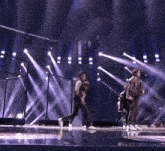 a group of men are dancing on a stage with purple lights behind them