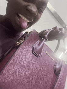 a woman sticking her tongue out while holding a michael kors bag