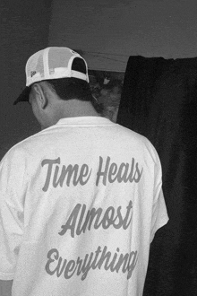 a man wearing a hat and a white shirt that says time heals almost everything
