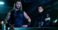 thor and captain america are standing next to each other in a room and talking .
