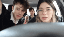 a group of people are sitting in a car and one of them has glasses on