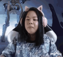 a woman wearing a cat ear headband is sitting in a chair with a robot in the background .