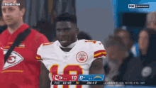 a man in a chiefs jersey stands in front of a scoreboard during a football game