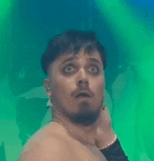 a shirtless man with a beard is making a funny face while holding his neck .