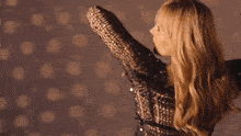 a woman in a sequined dress is standing with her arms outstretched .