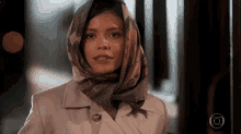 a woman wearing a scarf around her head and a white jacket