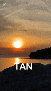 a sunset over a body of water with the word tan