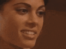 a close up of a woman 's face smiling in a dark room .