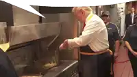 a man in a white shirt and blue apron is cooking french fries in a mcdonald 's kitchen
